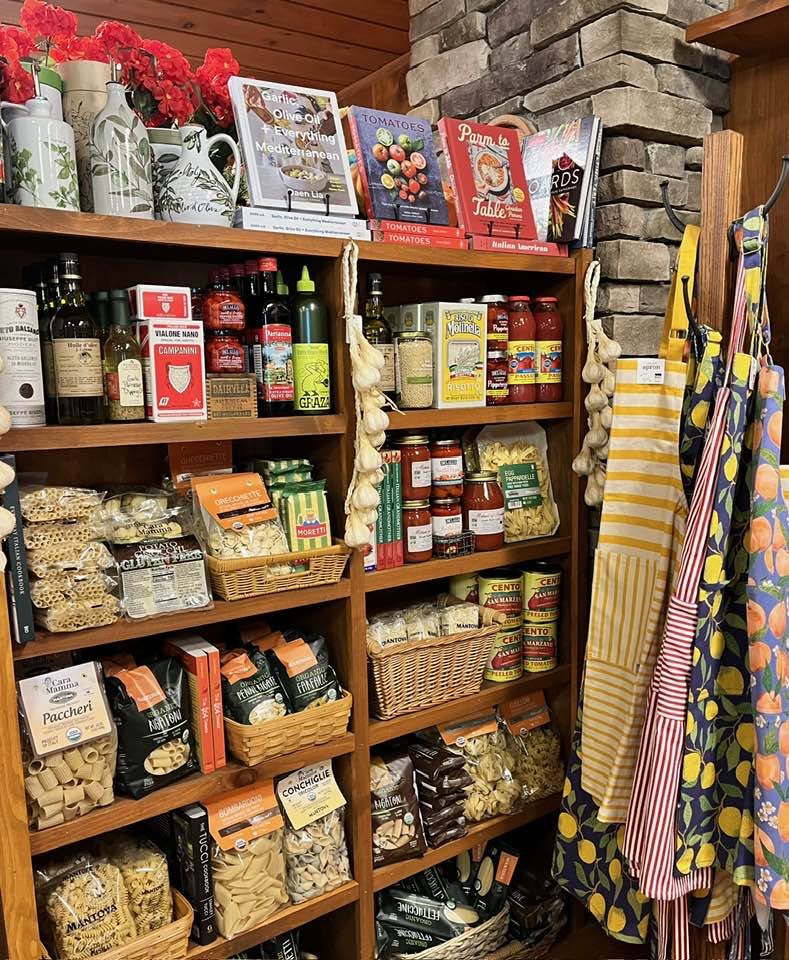 Shelves of pasta, sauces, olive oil, books, and aprons